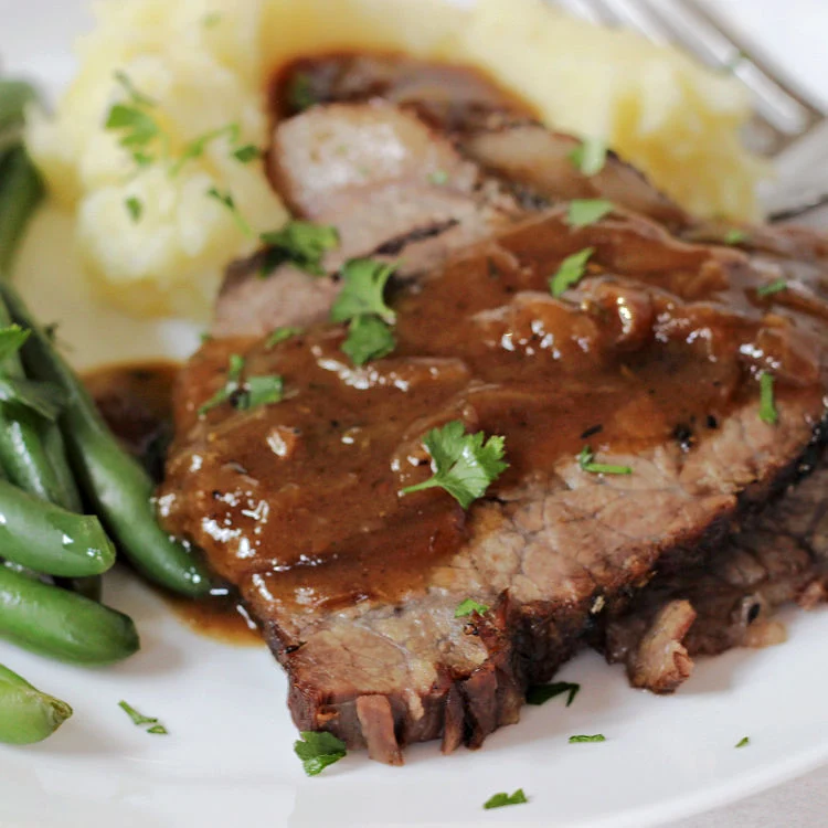 slices of Tender Beef Bottom Round Roast recipe with Gravy on a plate ready to eat
