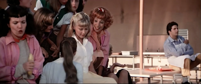 Who is this lonely background extra from the movie, Grease? Why is he stalking Olivia Newton-John. Is he a ghost?