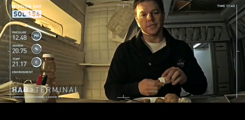 Matt Damon facing camera marked up with observational data in galley of his Mars habitat