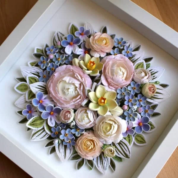 pastel paper sculpture and quilled spring flower arrangement including peony, forget-me-not, daffodils, and violets in square white frame