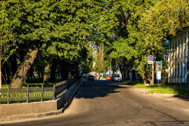 Дорога в городе вдоль металлической ограды сквера