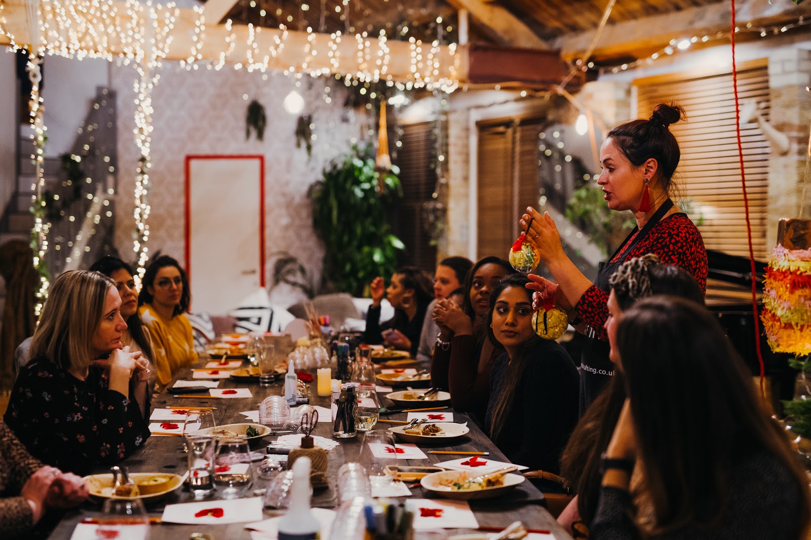 Bloggers being shown how to make a bauble over a long dining table.