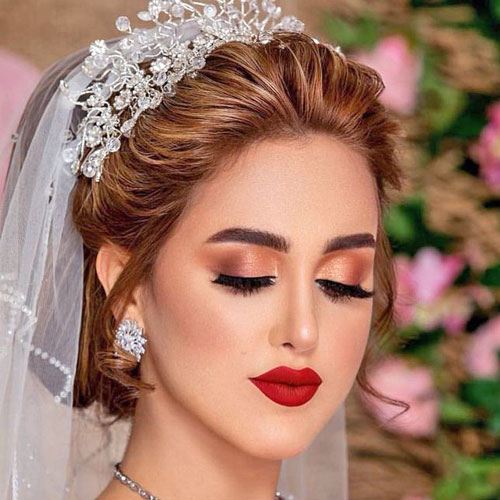 Maquillaje de novia con sombra de ojos naranja y labios rojos