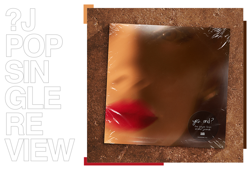 A vinyl of Ariana Grande’s single “Yes, And?” lying on a brown concrete surface.  The cover features a blurred, out of focus close-up of half of Ariana Grande’s face, and she is wearing bright red lipstick.