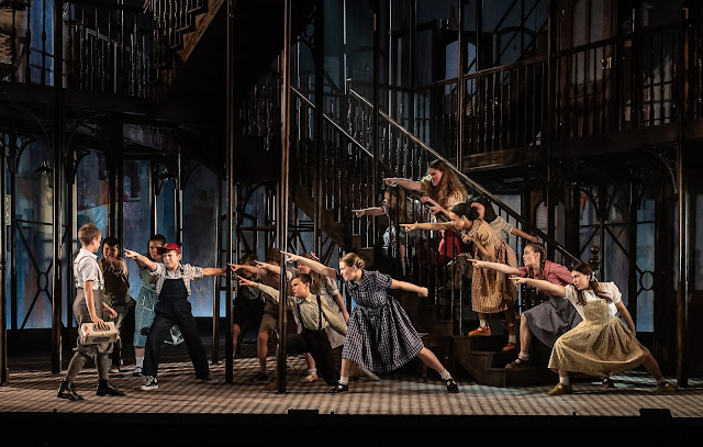 Kurt Weill: Street Scene - Oliver Wright as Charlie Hildebrand (far left), Louis Parker as Willie Maurrant (red cap) and children- Opera North (Photo Clive Barda)