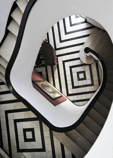 gorgeous circular stair case foyer with black and white tile geometric pattern
