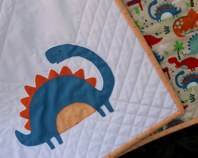 blue dinosaur appliqued baby quilt block with blanket stitching