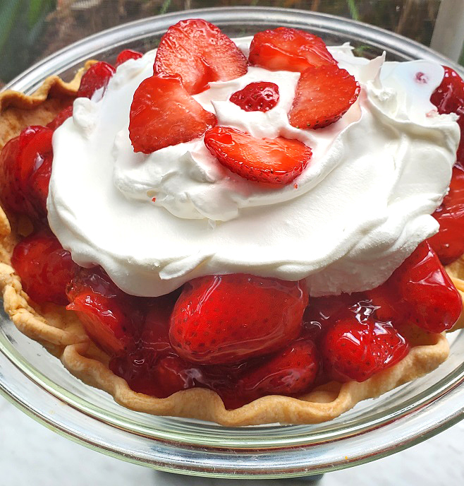 An all homemade pie with crust recipe, filled with fresh strawberries, a jello strawberry glaze and topped with whipped cream