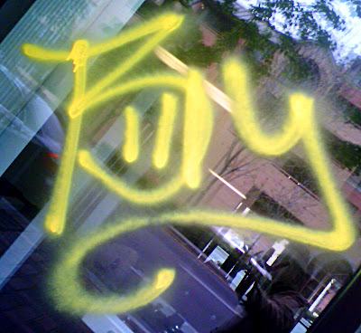 Close up of the word Billy spray painted in yellow spray paint on the window of a condo gym at 235 on Market