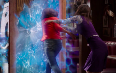 Janet shoves a demon through the portal, which is a large wooden door with a watery blue electric field in the middle.