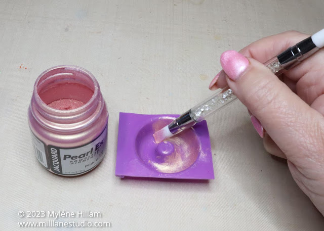 Pink mica powder being applied to a donut shaped silicone mould with a silicone nail tool