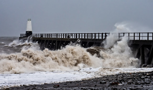 Photo of giant waves breaking on the shore and pier at Maryport