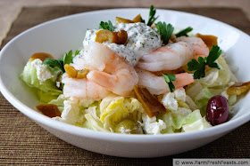 photo of a bowl of Mediterranean shrimp salad atop a bed of lettuce with spiced Greek yogurt, olives, and feta cheese