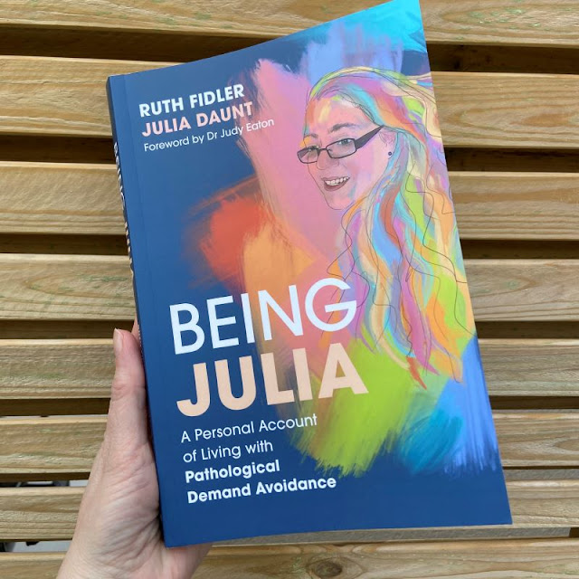 Blue front cover of Being Julia book with title text and text saying a personal account of living with pda. also has colourful line drawing of Julia
