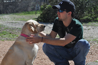 Darrell and Egypt out in the yard, he is squating down with her in front of him, they are looking at each other but Egypts eyes are shut because she is facing the sun.