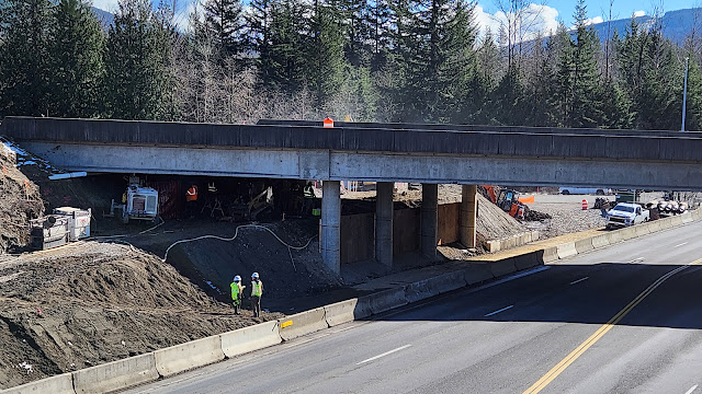 Crews work underneath the eastbound lanes of Interstate 90 over State Route 18. Concrete barrier separates the work zone from SR 18.