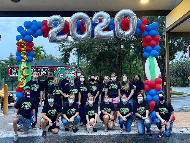 The entire graduation team under blue and red balloons