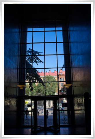 Fotat inifrån Stadsbiblioteket mot blå himmel, som speglar sig i väggarna