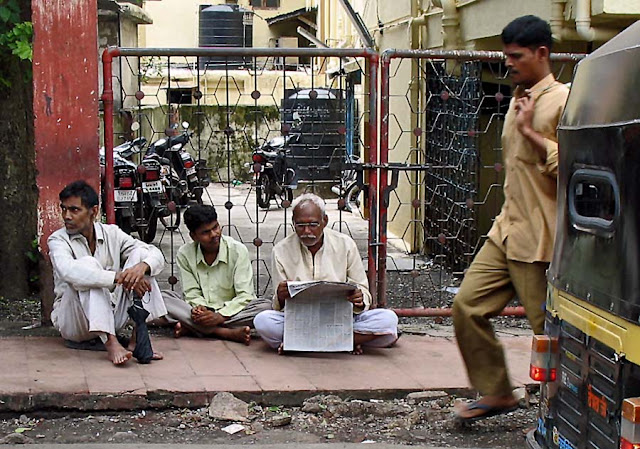 group of elderly men reading newspaper