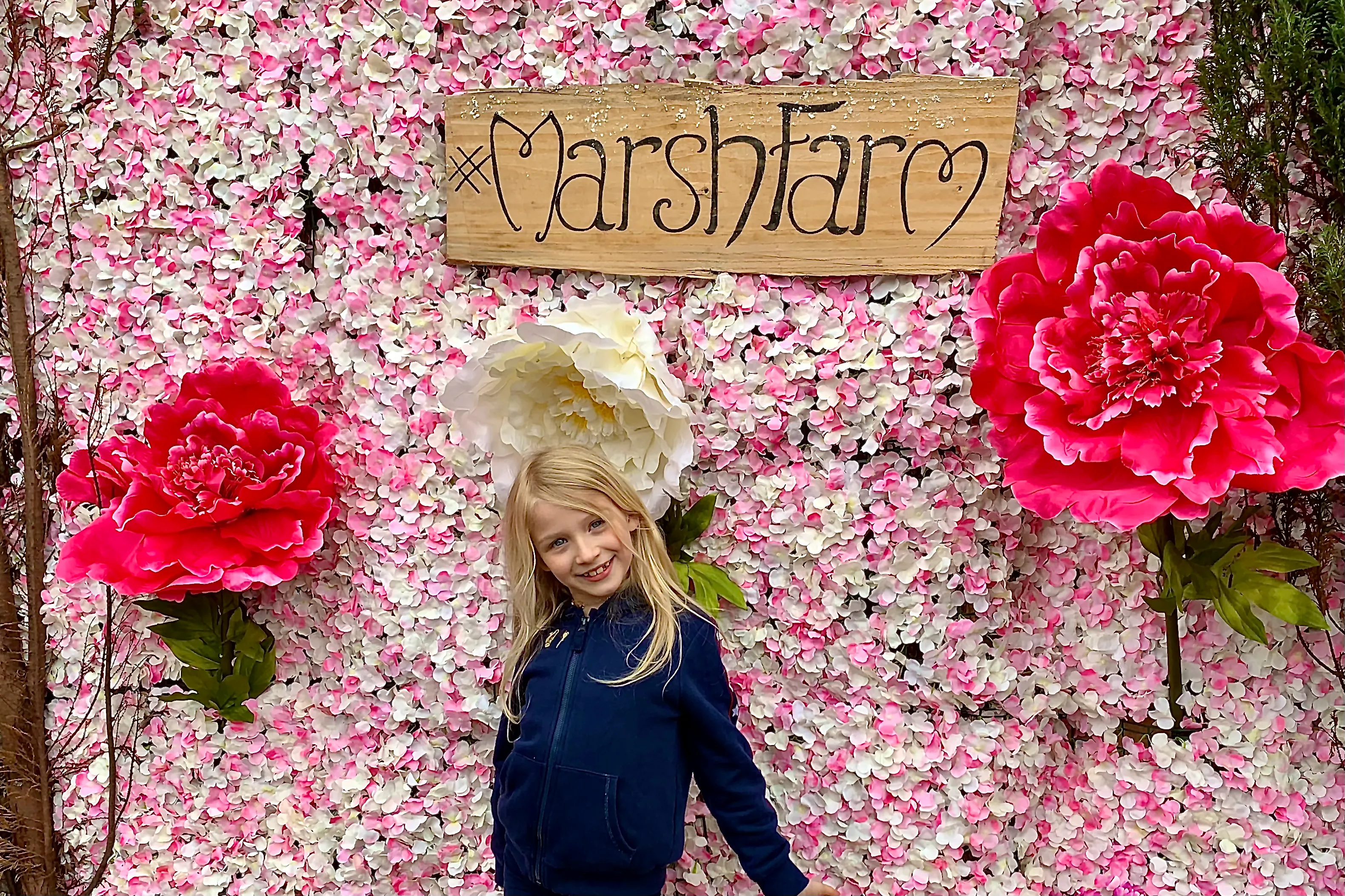 A young girl posing against a floral backdrop at Marsh Farm in Essex