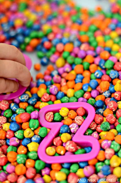 Sensory & literacy activity for kids using rainbow dyed chickpeas and alphabet cookie cutters from And Next Comes L