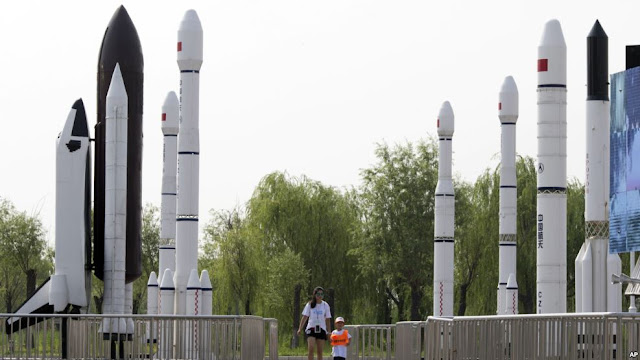 A woman walks with a child as they visit a park displaying replicas of foreign and domestic space vehicles in Beijing, China, June 26, 2016. China and the United States announced a new round of talks with China about civil space exploration.