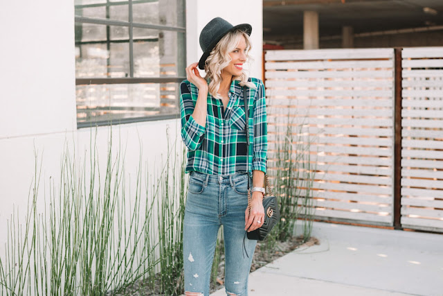 A woman wears a flannel shirt with jeans.