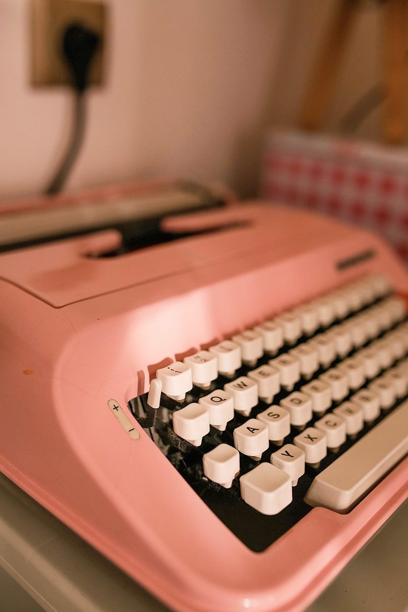 a cozy, aesthetic shot of a pink typewriter on top of a table