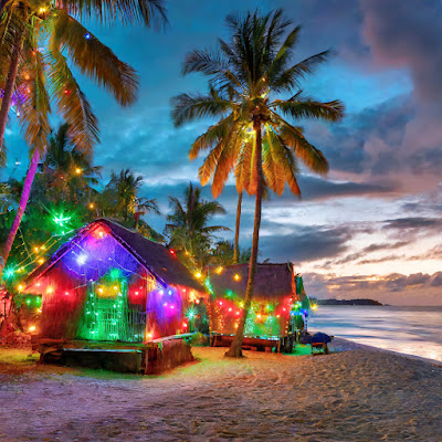 wooden village houses on tropic beach at dusk with christmas lights