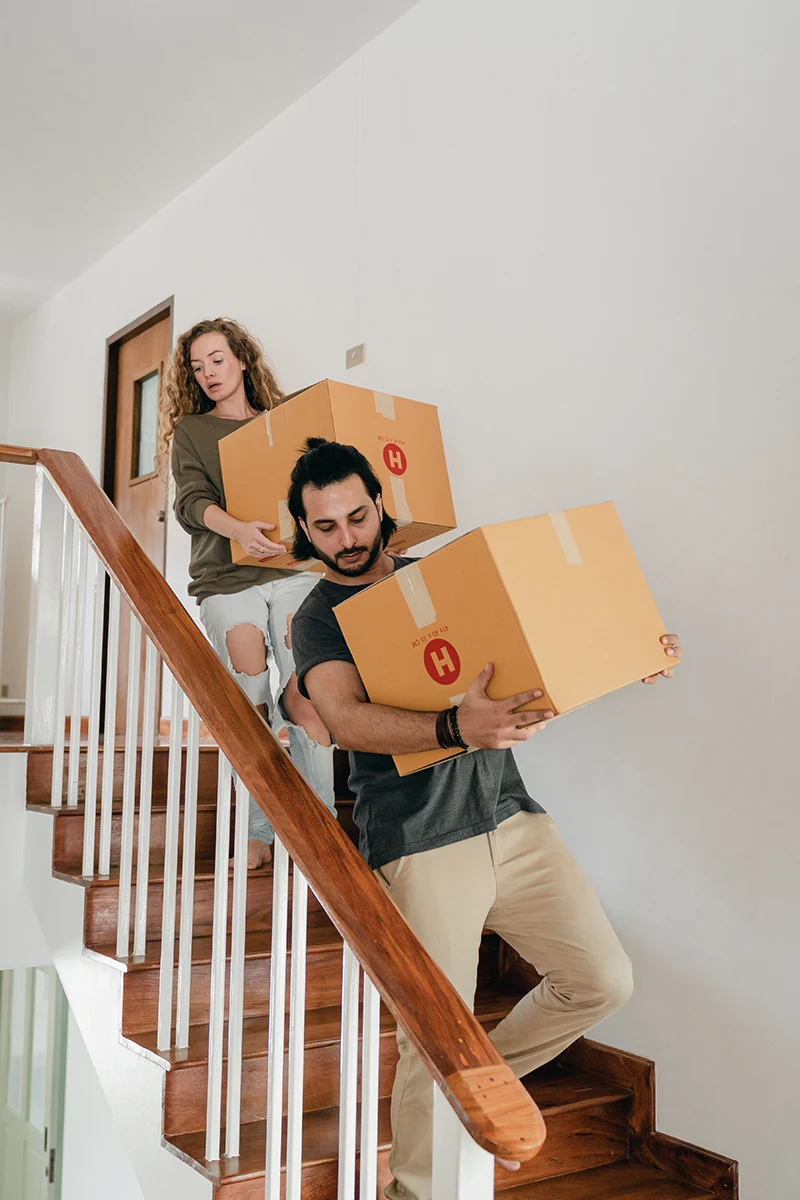 couple with cardboard boxes moving downstairs