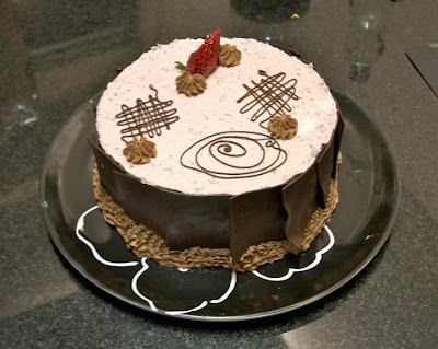 Torta feita com discos de suspiro, creme de chocolate, creme de frutas vermelhas e decorada com chocolate meio amargo. 