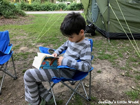 Child reading by a tent