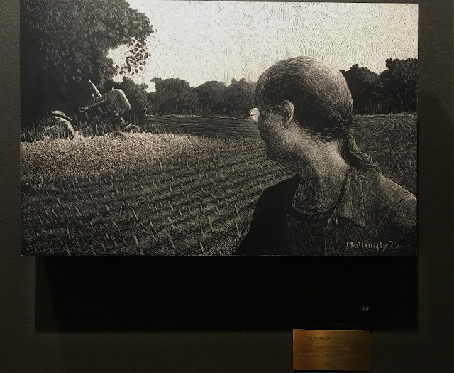 Scratchboard drawing hanging on gallery wall. A middle-aged man looks back over his shoulder at a discarded tractor lurking in a patch of trees by a plowed field of stubble in late afternoon light.