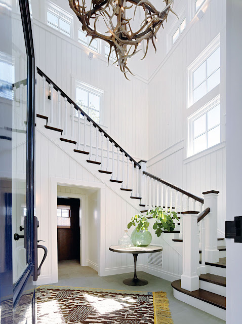 Dramatic white entry with antler chandelier and staircase in Napa Valley farmhouse by Ken Fulk in C Magazine