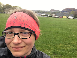 A selfie of me in a pink headband with a grassy field behind me.