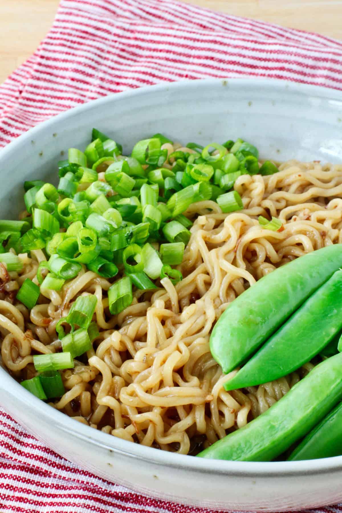Bowl of Brothless Ramen with XO Sauce (XO Mazemen) topped with scallions and sugar snap peas in a bowl.