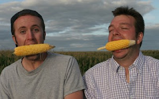 Photo of Curt and Ian with ears of corn in their mouths