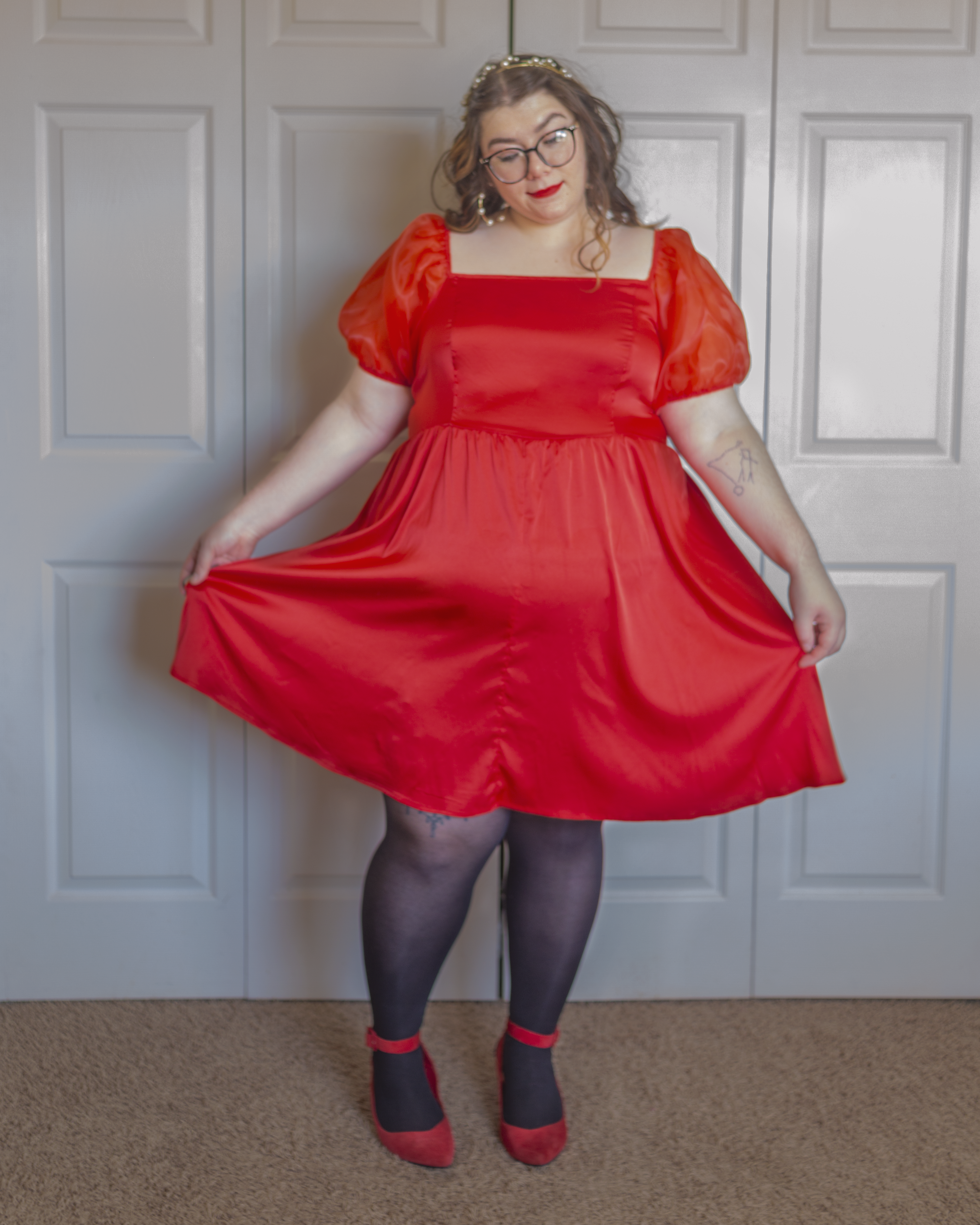 An outfit consisting of a short red puffy sleeve midi dress, black tights and red ankle strap heels.
