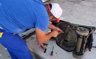 Halil works to fix the belt on the mower