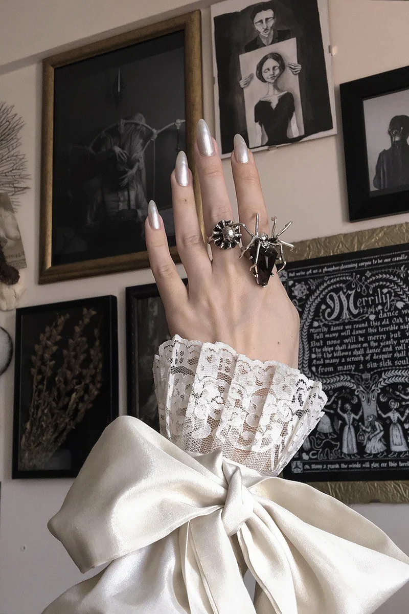 a close-up of woman hand with silver rings in a style of Dark Academia Aesthetic