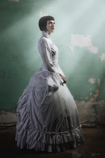 A Vulcan Victorian stands in a ray of sunlight with an opulent, full skirted gown