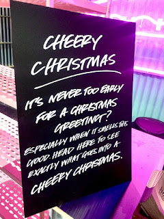 A big black board with Cheery Christmas in informal white font on a bright background. 