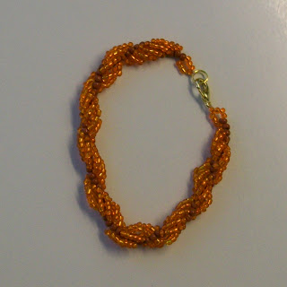 A bracelet of beaded spiral rope in orange colors