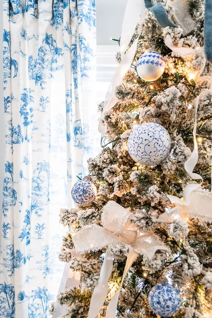 blue and white ornaments on flocked tree, blue toile curtains