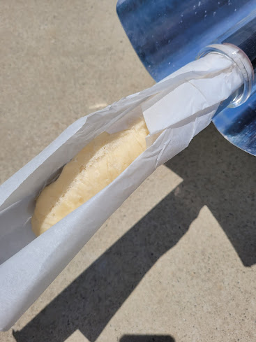 The GoSun canister is being pulled out of the solar oven with a mostly-cooked loaf of bread in it