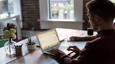 Man working in affiliate marketing work station with working tools, a computer, pens and pencils and potted plants on the work table.