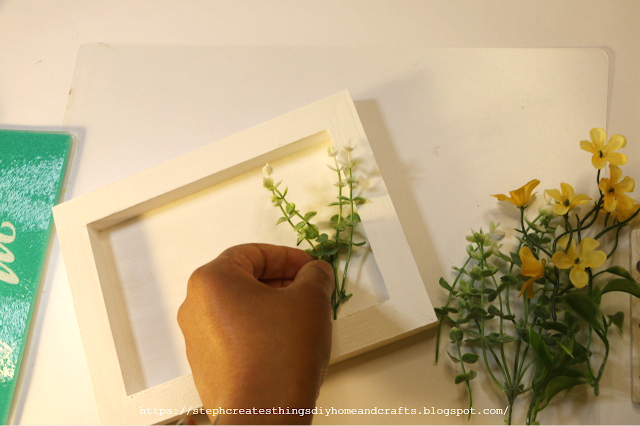 faux floral being placed inside of painted wooden box sign