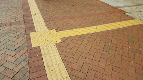 junction on a sidewalk marked with the raised beads and straight lines
