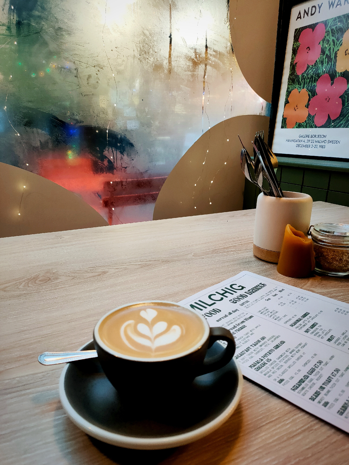 A flat white in a grey cup on a wooden table in a cafe