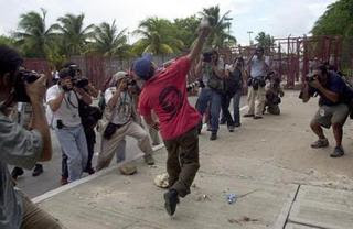 Anti-WTO protester photographed as throws rocks over a fence towards police